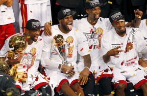 Heat's James holds the Bill Russell MVP Trophy as Wade (L) holds the Larry O'Brien Trophy while Bosh celebrates after their team defeated the Spurs in Game 7 to win their NBA Finals basketball playoff in Miami